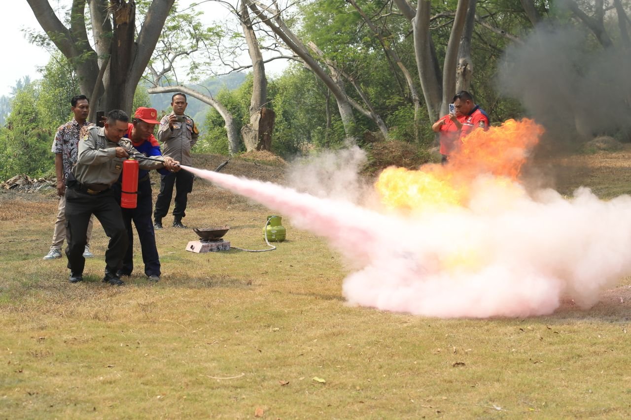 services-01 Fire safety training exercise with participants using a fire extinguisher in a rural outdoors setting.